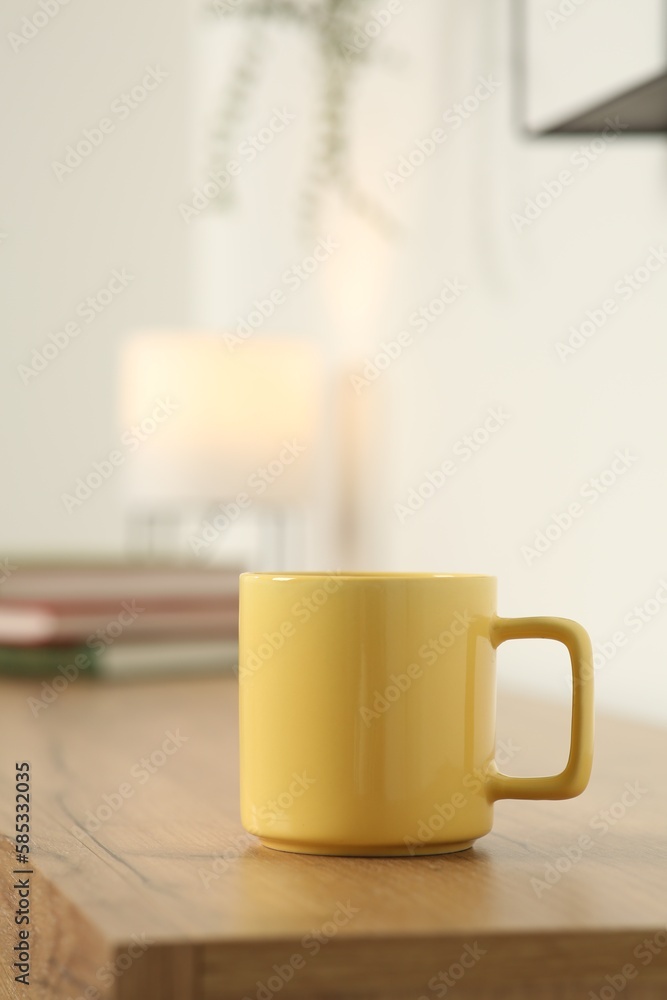 Yellow mug on wooden table indoors. Mockup for design Yellow mug on wooden table indoors. Mockup for design