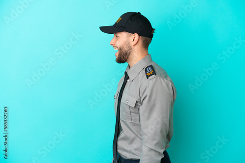 Young security man isolated on blue background laughing in lateral position © luismolinero