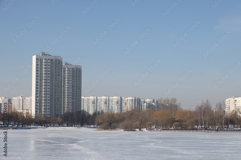 Obraz premium Landscapes in the park with melting snow, puddles and ice in spring. Residential buildings and spring landscapes of Butovo, Moscow, thawed patches, March 2023.
