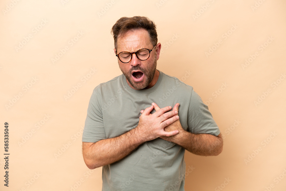 Middle age caucasian man isolated on beige background having a pain in the heart Middle age caucasian man isolated on beige background having a pain in the heart