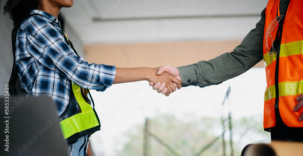 Construction team shake hands greeting start new project plan behind yellow helmet in office center to consults about their building project.. Construction team shake hands greeting start new project plan behind yellow helmet in office center to consults about their building project..