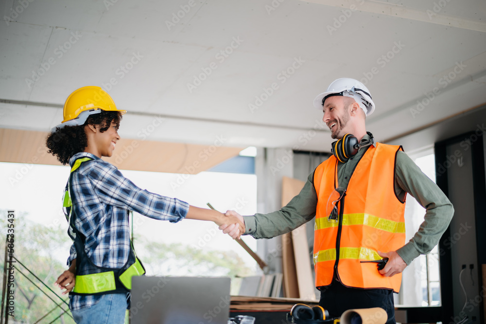 Construction team shake hands greeting start new project plan behind yellow helmet in office center to consults about their building project.. Construction team shake hands greeting start new project plan behind yellow helmet in office center to consults about their building project..