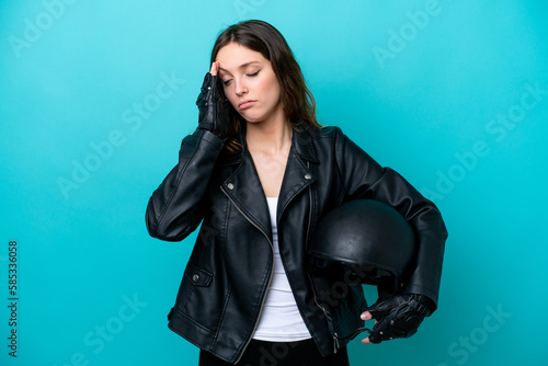 Young caucasian woman with a motorcycle helmet isolated on blue background with headache