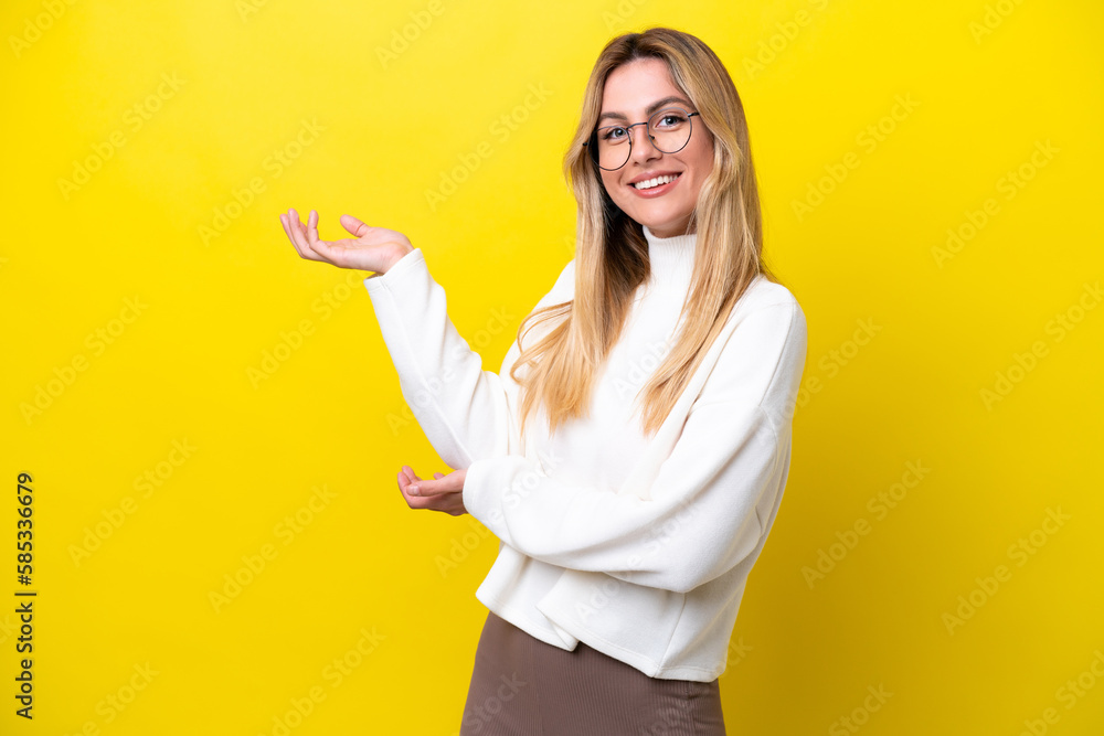 Young Uruguayan woman isolated on yellow background extending hands to the side for inviting to come Young Uruguayan woman isolated on yellow background extending hands to the side for inviting to come