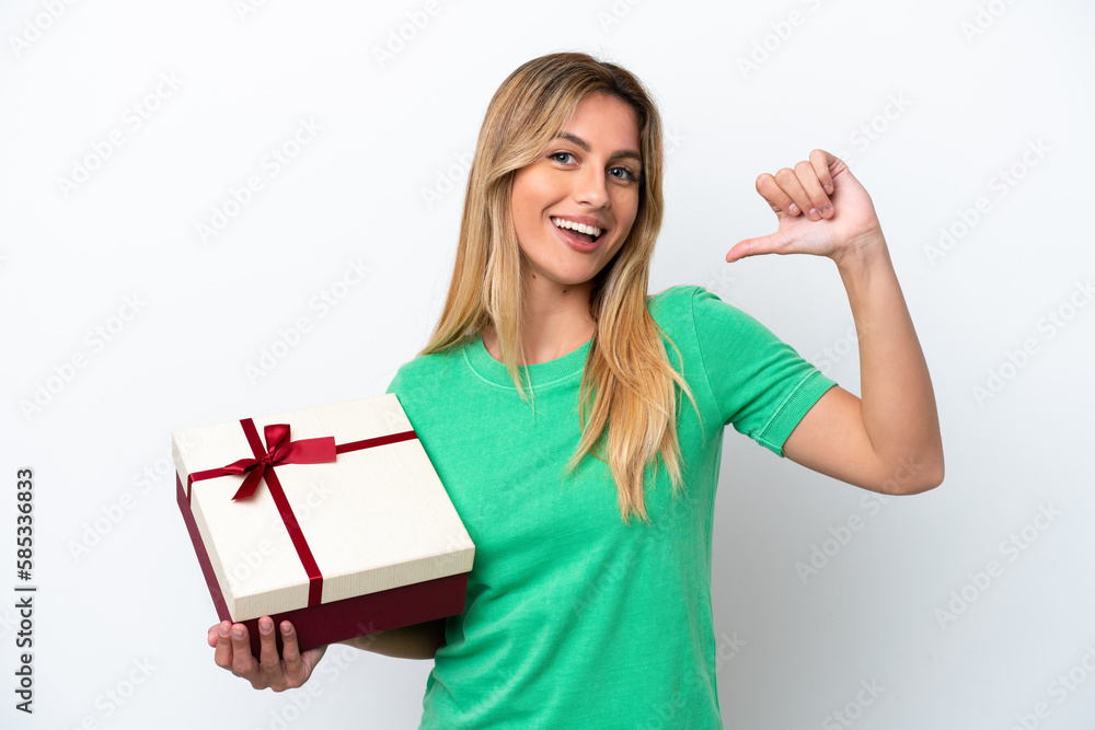 Young Uruguayan woman holding a gift isolated on white background proud and self-satisfied Young Uruguayan woman holding a gift isolated on white background proud and self-satisfied