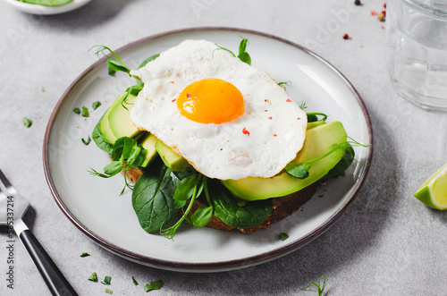Avocado Sandwich with Fried Egg, Spinach and Green Sprouts, Healthy Breakfast or Snack on Bright Background