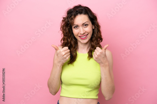 Young caucasian woman isolated on pink background with thumbs up gesture and smiling