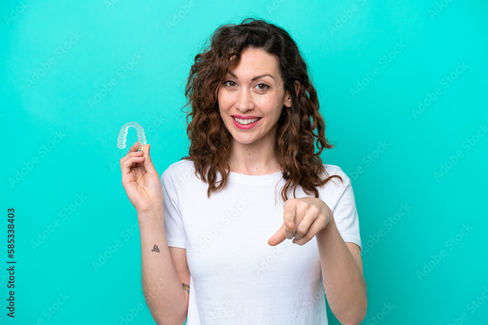 Fototapeta premium Young caucasian woman holding a envisaging isolated on blue background points finger at you with a confident expression