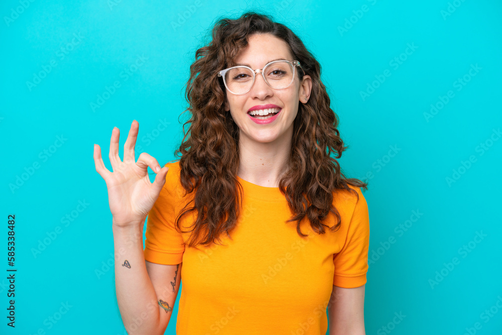 Young caucasian woman isolated on blue background With glasses and doing OK sign Young caucasian woman isolated on blue background With glasses and doing OK sign