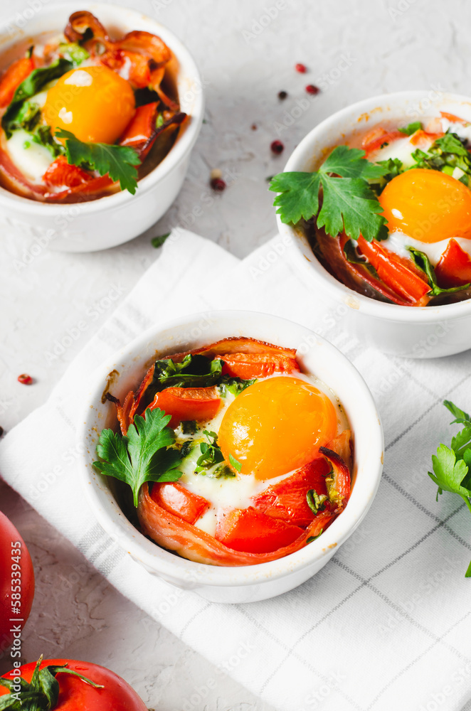 Baked Eggs with Bacon, Tomatoes, Spinach and Herbs on Bright Background, Healthy Breakfast or Snack Baked Eggs with Bacon, Tomatoes, Spinach and Herbs on Bright Background, Healthy Breakfast or Snack