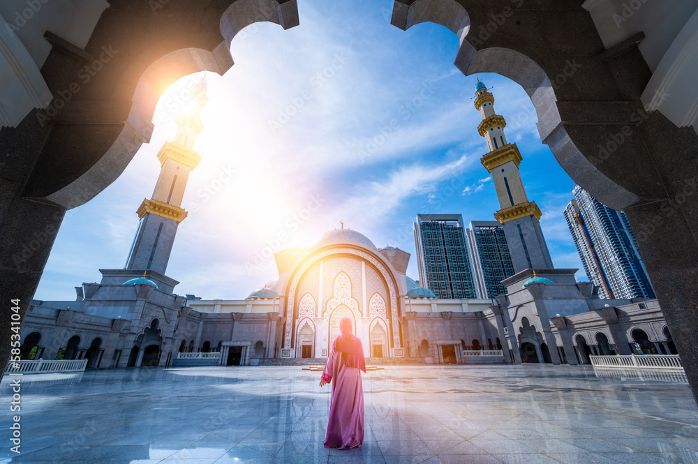 Obraz premium Woman dressed in islamic clothing in Masjid Wilayah Persekutuan (Federal Territory Mosque), and sunlight in Kuala Lumpur, Malaysia.