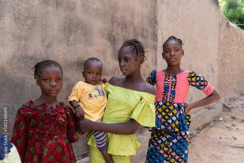 Group of young african girls with a baby boy posing in front of a wall - concept of human population overshoot photo