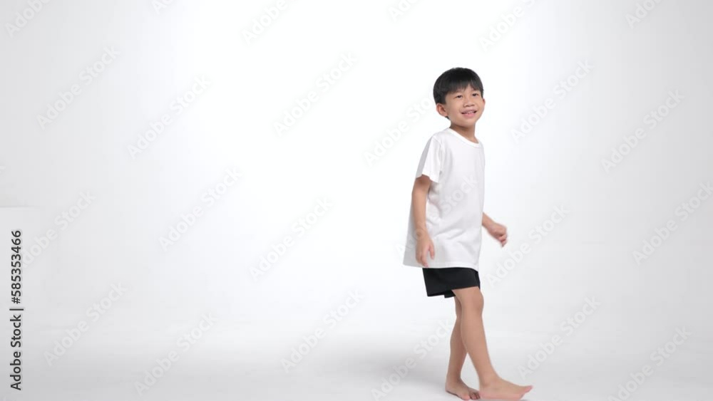Asian kid practice dancing on the white screen. A 6 year old boy in casual shirt learning new move by himself.