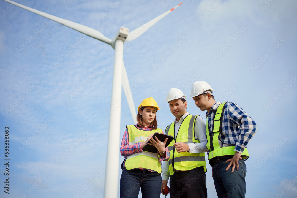 Team of asian engineers discussing and checking turbines on wind turbine farm. Renewable energy technology and sustainability. Team of asian engineers discussing and checking turbines on wind turbine farm. Renewable energy technology and sustainability.
