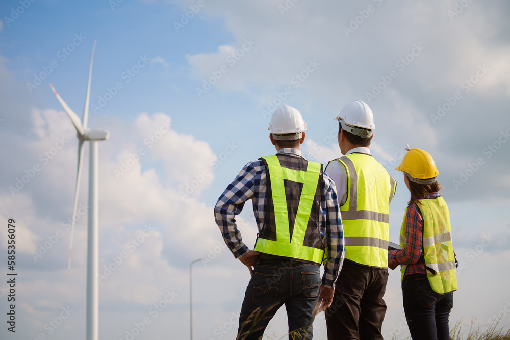 Back view of three engineers discussing and checking turbines on wind turbine farm. Renewable energy technology and sustainability. Back view of three engineers discussing and checking turbines on wind turbine farm. Renewable energy technology and sustainability.
