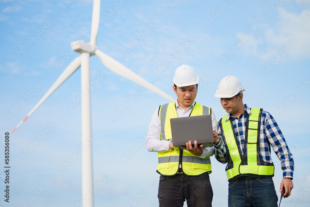 Two asian engineers discussing and checking turbines on wind turbine farm. Renewable energy technology and sustainability. Two asian engineers discussing and checking turbines on wind turbine farm. Renewable energy technology and sustainability.