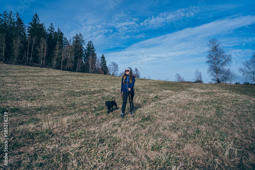 Woman with backpack hiking in remote sunny rural field.