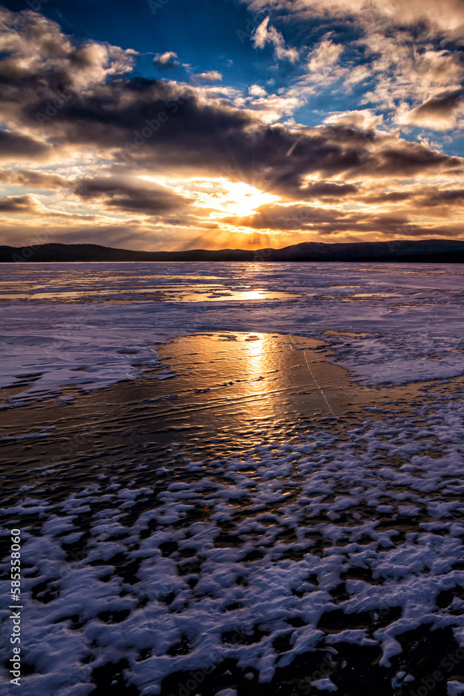 Lake covered with ice against the backdrop of sunset