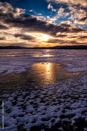Lake covered with ice against the backdrop of sunset