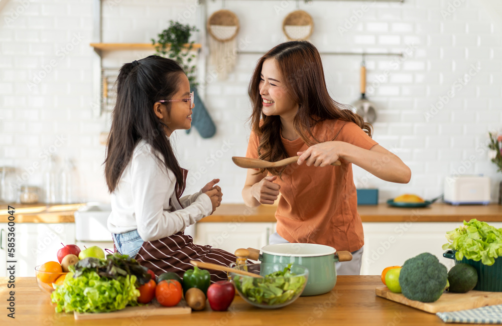 Portrait of enjoy love asian family mother with little asian girl daughter child help cooking food healthy eat with fresh vegetable testing smell soup in a pot with spoon.helping mommy in kitchen
