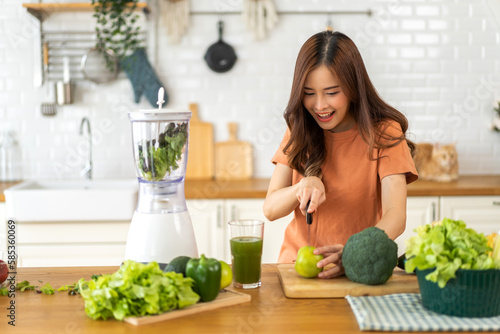 Portrait of beauty healthy asian woman making green vegetables detox vegan and green fruit smoothie with blender.young girl drinking glass of green fruit smoothie in kitchen.Diet concept.healthy
