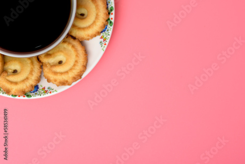 Herbata i ciastko w lewym rogu zdjęcia na różowym tle