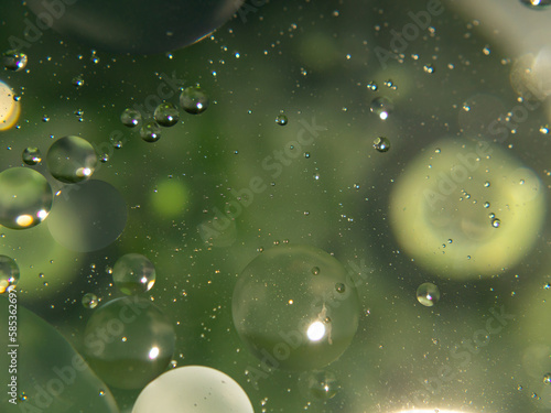 A close up of oil drops in a green and Blurred background