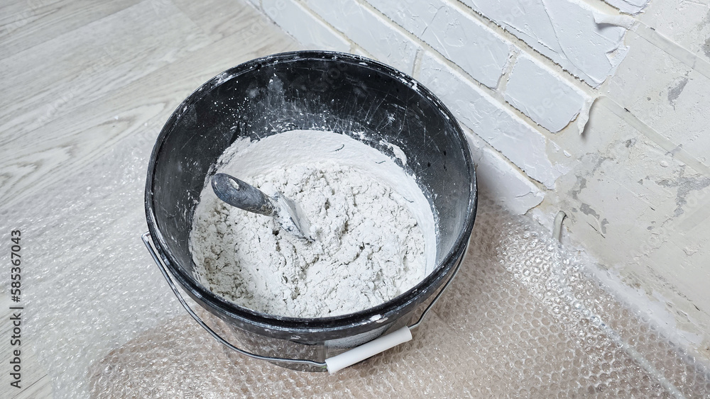 white putty cement in black bucket on floor for rebuild wall at home white putty cement in black bucket on floor for rebuild wall at home