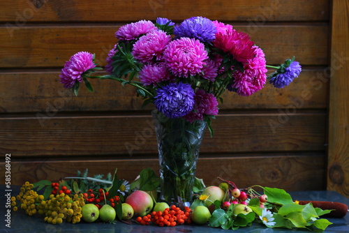 A bouquet of asters stands in a vase against the background of a wooden wall photo