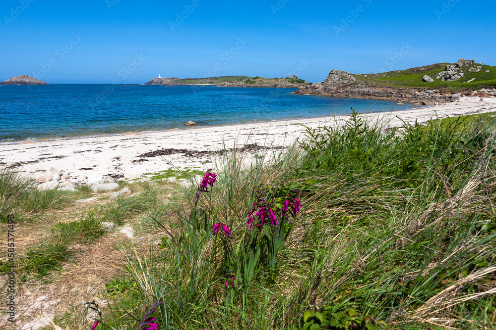 Gimble Porth on the north-east coast of Tresco, Isles of Scilly, UK, with the lighthouse on Round Island visible in the distance