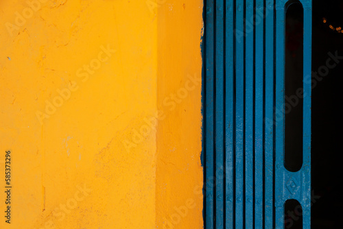 Yellow and blue abstract background divided in two halves vertically. Brightly colored wall and folding gate of a Vietnamese house