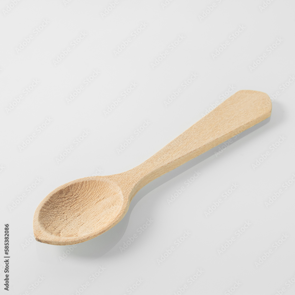 Wood kitchen utensils. Wooden tea spoon on a white mirror background Wood kitchen utensils. Wooden tea spoon on a white mirror background