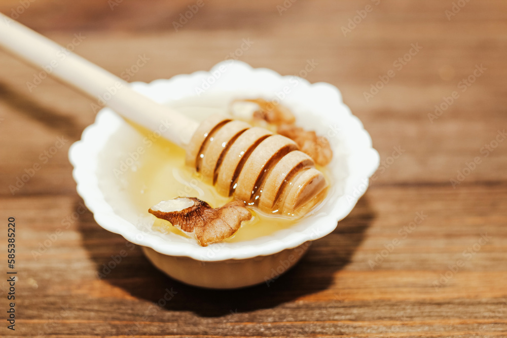 Liquid organic honey in white bowl, wooden honey spoon. Liquid organic honey in white bowl, wooden honey spoon.