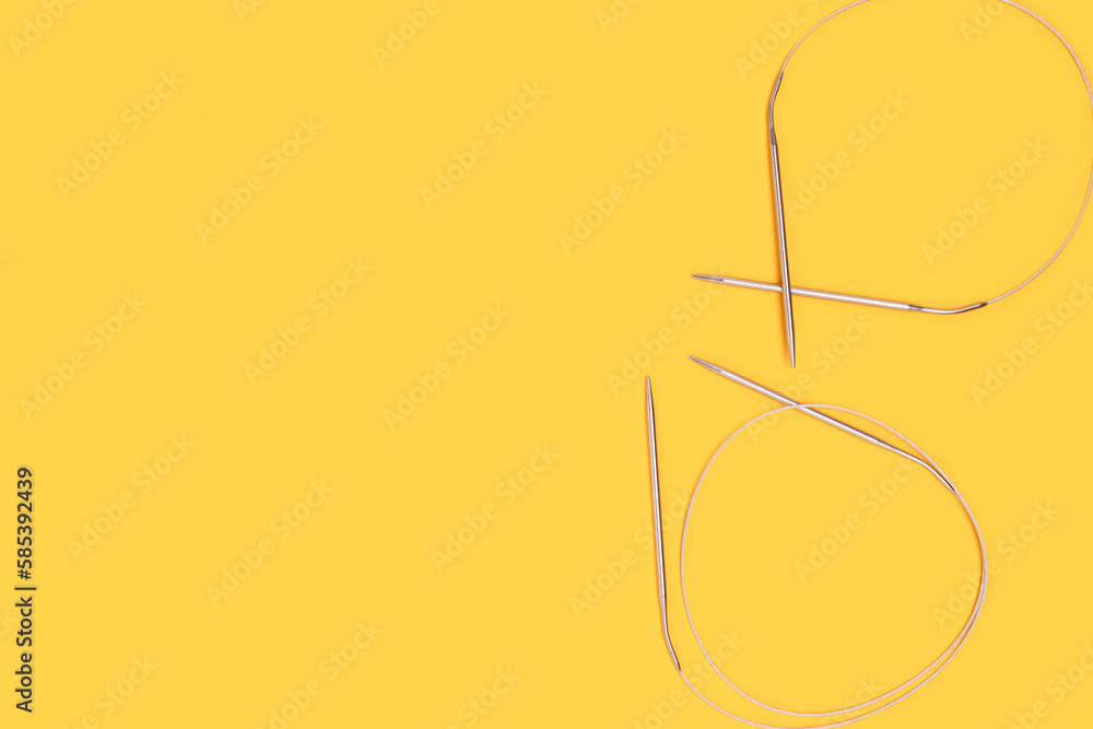 Knitting needles on a yellow background. Hobby accessories with copy space.