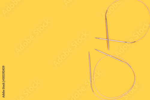Knitting needles on a yellow background. Hobby accessories with copy space.