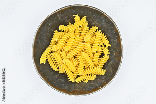 Fussili pasta in a dark grey bowl, isolated on a white background