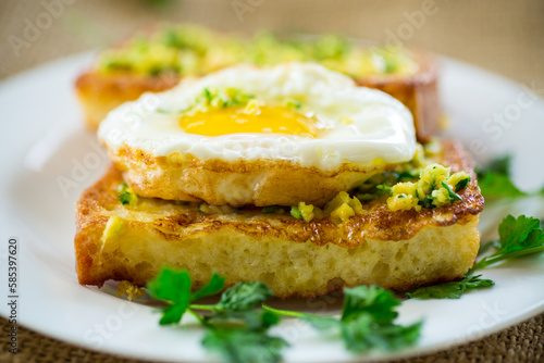 Fried croutons in batter with garlic and herbs and a fried egg in a plate.