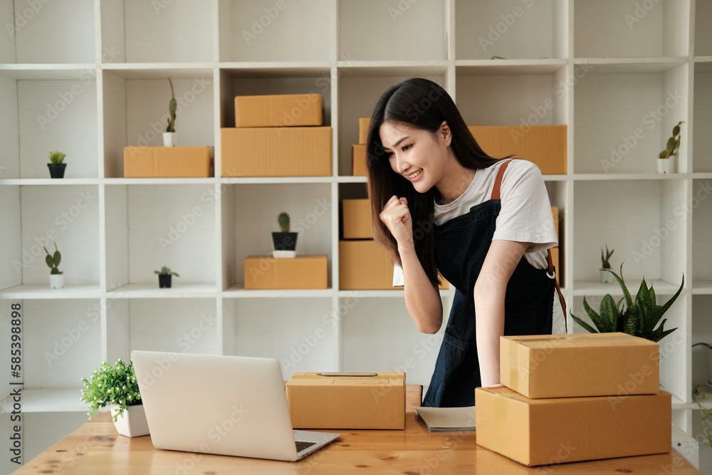Startup SME small business entrepreneur of freelance Asian woman using a laptop with box Cheerful success happy Asian woman her hand lifts up online marketing packaging and delivery SME idea concept Startup SME small business entrepreneur of freelance Asian woman using a laptop with box Cheerful success happy Asian woman her hand lifts up online marketing packaging and delivery SME idea concept