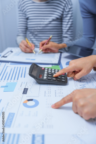 Using calculator, small business accounting team meeting three asian people with salary monthly charts data, basic business accounting and bookkeeping concept.