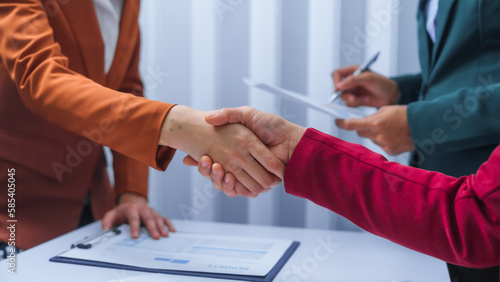 Shaking hands, small business accounting team meeting three asian people with salary monthly charts data, basic business accounting and bookkeeping concept.