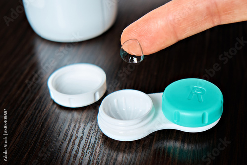 A demonstration of a contact lens for the eyes, a container for their storage and a bottle of liquid in the background. The topic of medicine and health care. Close-up