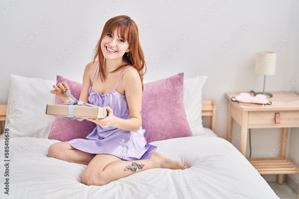 Young woman wearing nightgown holding birthday gift at bedroom Young woman wearing nightgown holding birthday gift at bedroom