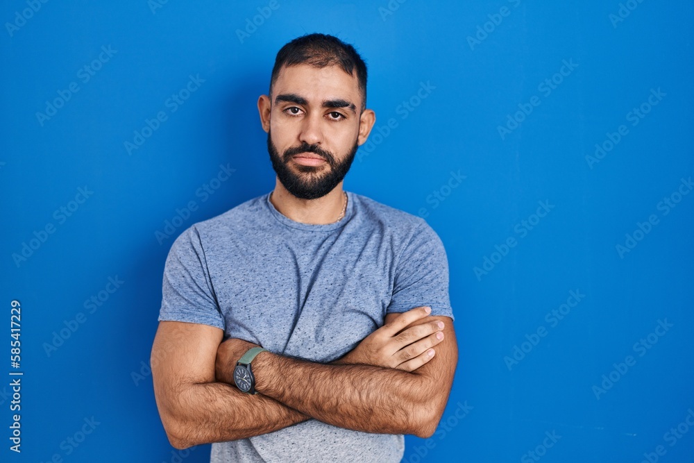 Middle east man with beard standing over blue background looking sleepy and tired, exhausted for fatigue and hangover, lazy eyes in the morning. Middle east man with beard standing over blue background looking sleepy and tired, exhausted for fatigue and hangover, lazy eyes in the morning.