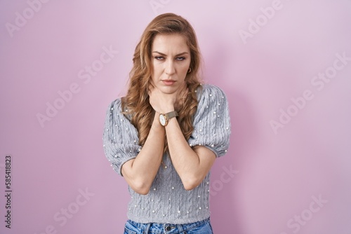Beautiful blonde woman standing over pink background shouting suffocate because painful strangle. health problem. asphyxiate and suicide concept.