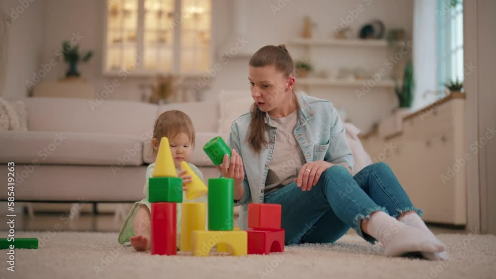 Mom building castle with her baby girl daughter from plastic blocks