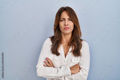 Hispanic woman standing over isolated background skeptic and nervous, disapproving expression on face with crossed arms. negative person.