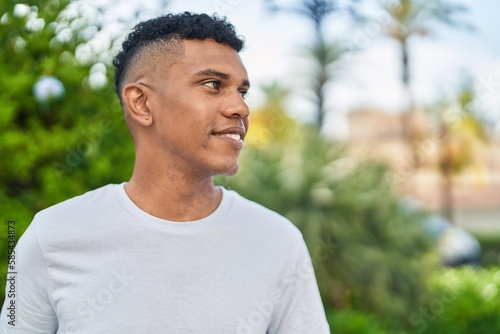 Young latin man smiling confident looking to the side at park
