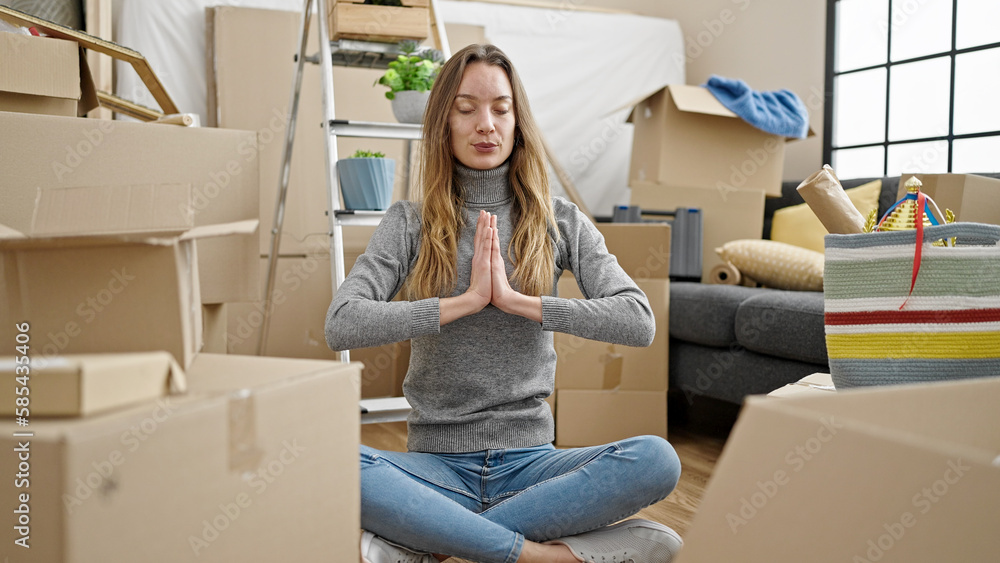 Young caucasian woman doing yoga exercise sitting on floor at new home Young caucasian woman doing yoga exercise sitting on floor at new home