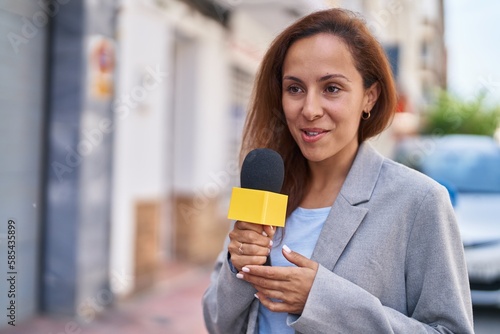 Young woman reporter working using microphone at street