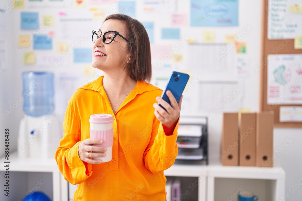 Middle age woman business worker using smartphone drinking coffee at office
